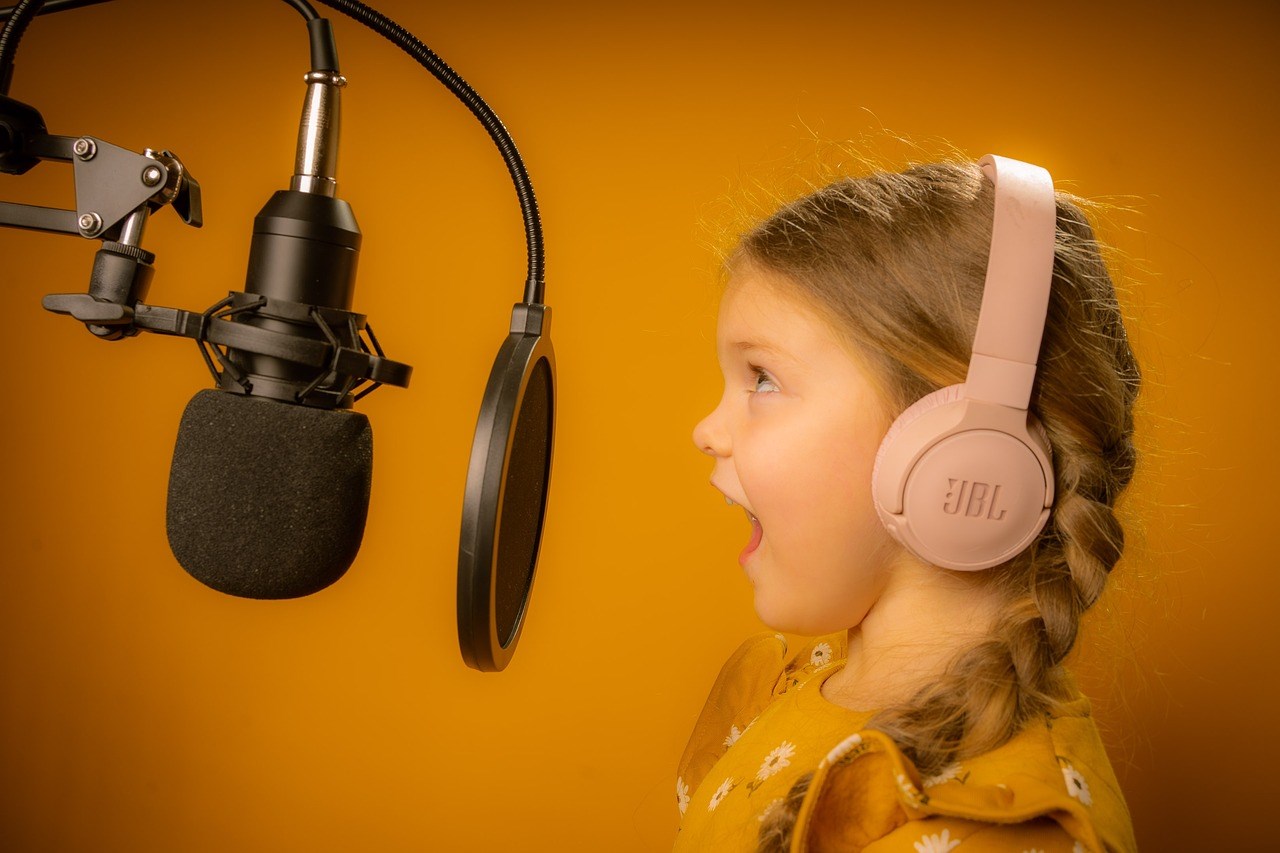 young girl with headphones singing into a microphone